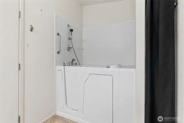 Accessible walk-in tub with grab bars and handheld shower for added safety and comfort.