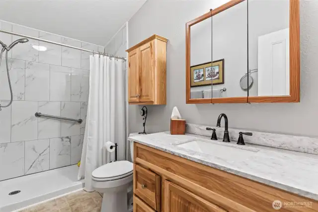Beautifully updated bathroom with new, floor-to-ceiling tile walk-in shower with grab bar and new vanity.