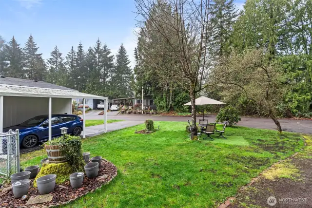 The spacious corner lot includes a landscaped lawn, shaded sitting area, and beautiful tree cover — your private nature retreat just steps from the home.