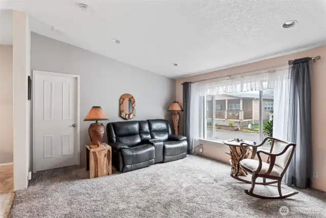 Bright and inviting living room with large windows, plush carpet, and cozy ambiance.