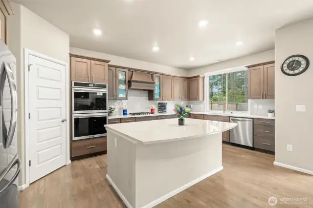 This chef-inspired kitchen features rich cabinetry, a large quartz island, double ovens, and stainless steel appliances—offering both style and functionality for everyday meals or entertaining a crowd.