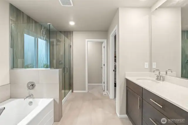 The spa-inspired ensuite bath features a luxurious soaking tub, oversized walk-in shower with floor-to-ceiling tile, dual-sink vanity, and access to a spacious walk-in closet—your private retreat for rest and relaxation.