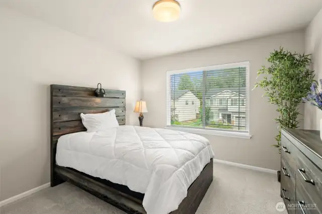 This bright and comfortable bedroom offers plush carpeting, a large window with neighborhood views, and plenty of space to unwind or get a good night’s sleep.