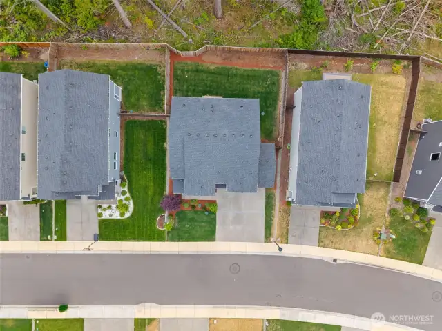 Bird’s-eye view of the property reveals a generous, fully fenced backyard backing to a greenbelt—providing added privacy and a peaceful natural buffer rarely found in suburban living.