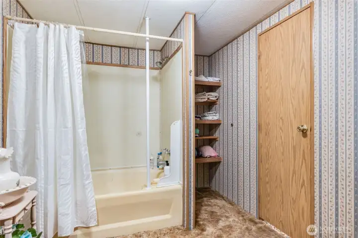 Full primary bath with shower-tub combo and built-in storage shelves.