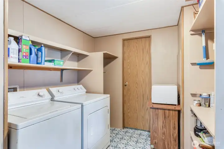Utility room with washer, dryer, and built-in storage shelves.