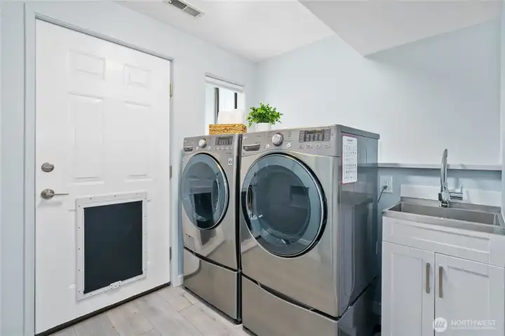 Lower level laundry room with sink and large doggie door to fenced yard