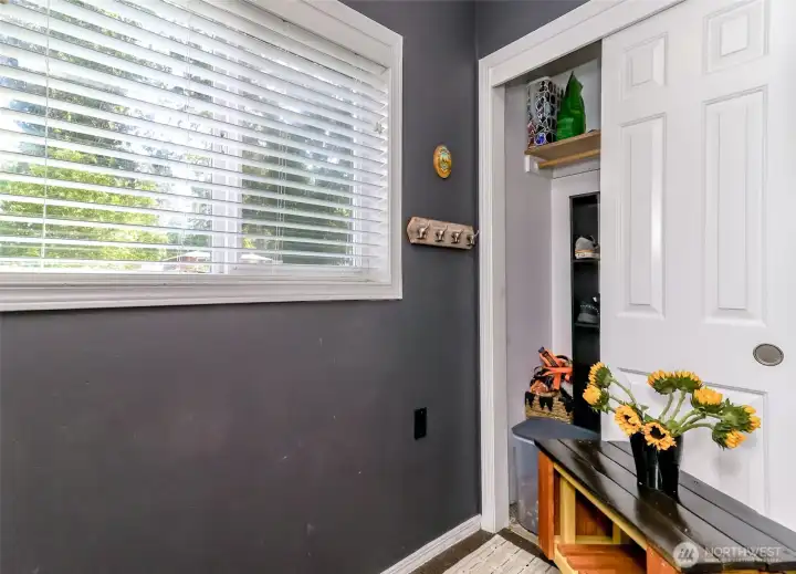 Bright, welcoming mudroom featuring a convenient coat closet and abundant natural light from a large window.