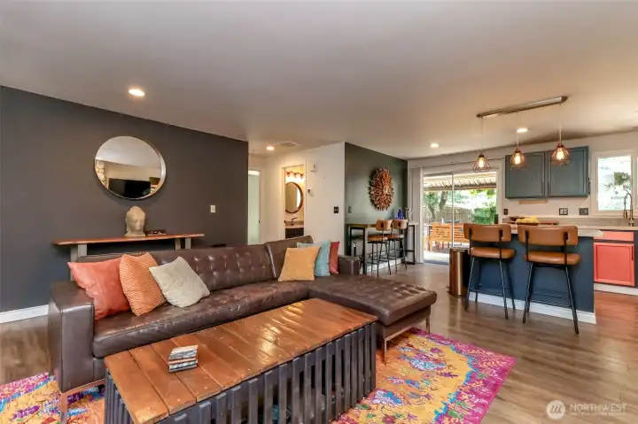 This Great Room opens seamlessly into a custom-painted kitchen, featuring beautiful laminate flooring throughout. The kitchen bar stools can remain with the property. The home showcases a unique, artistic flair and thoughtful design details in every room.