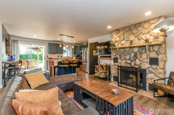 This Great Room opens seamlessly into a custom-painted kitchen, featuring beautiful laminate flooring throughout. The kitchen bar stools can remain with the property. The home showcases a unique, artistic flair and thoughtful design details in every room.