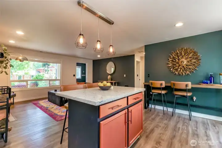 Another view of the great room, which opens into the custom-painted kitchen featuring beautiful laminate flooring. The bar stools are available to stay if desired.
