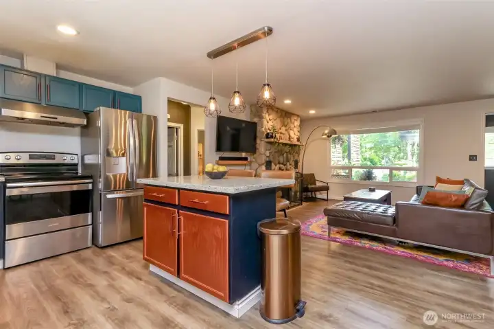 Great Room featuring an open concept layout leading into a custom-painted kitchen. Beautiful laminate flooring throughout. High-quality appliances are included, and the bar stools can stay if desired.