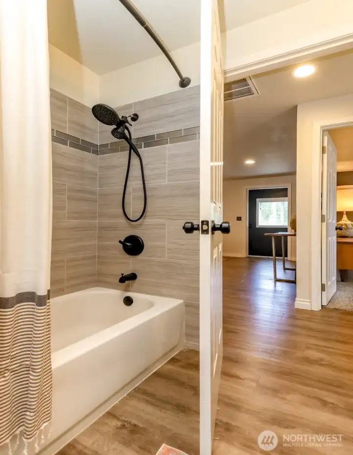 Updated primary bathroom featuring modern tile work and water-resistant laminate flooring.
