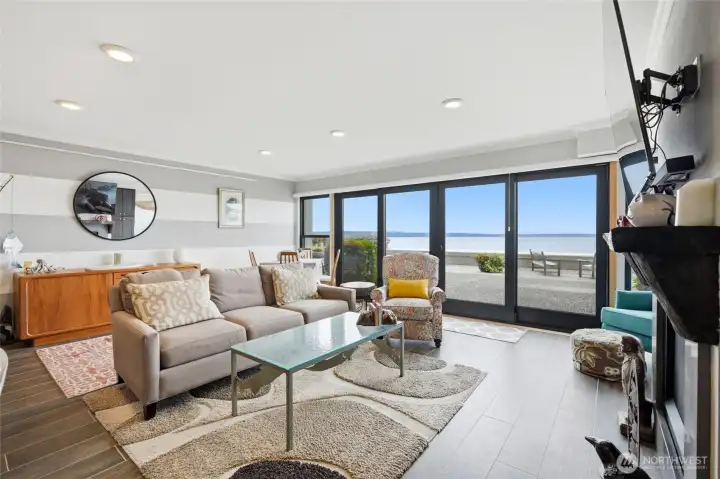 Bright waterfront living room with expansive glass doors framing beautiful Puget Sound and ferry views. Bright waterfront living room with expansive glass doors framing beautiful Puget Sound and ferry views.