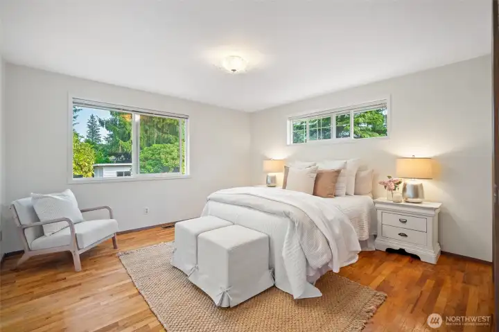 The peaceful primary bedroom with hardwood floors.