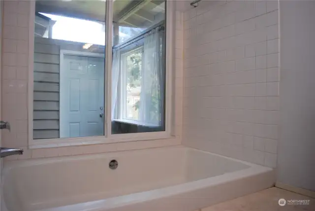 Soaker tub and shower overlook the atrium in the primary suite.