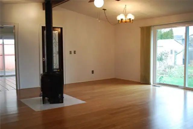 View from bedroom hall area across bamboo floored, cathedral ceiling great room towards the back slider and the kitchen & dining area.  Beautiful gas stove for warm comfort or emergency needs.