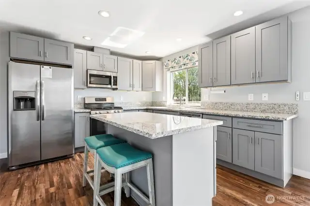 Coastal vibes with soft gray cabinets and stainless steel appliances.
