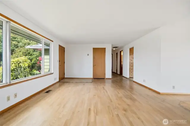 Living room and entry shown without virtual staging - original hardwood floors, wood trim and doors.