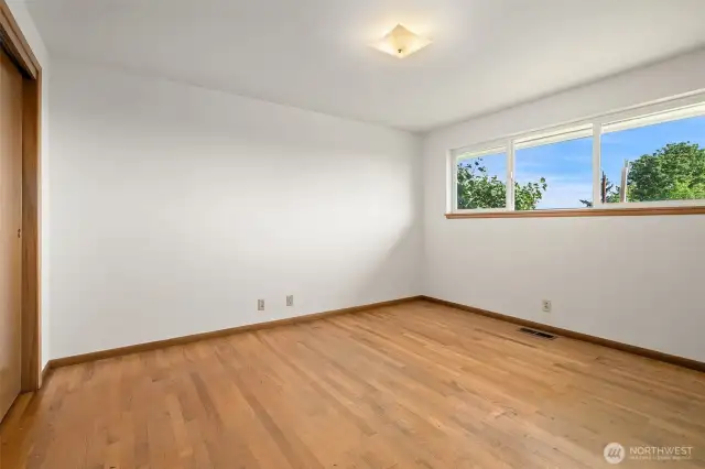 Primary bedroom shown here without the virtual staging. Original hardwoods, wood doors and trim all unpainted!