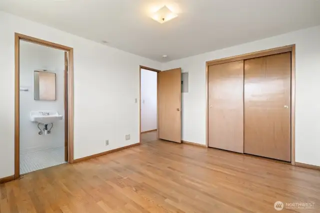 Primary bedroom showing closets, access to bathroom and original hardwoods.