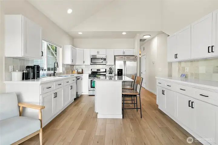 The kitchen is the true heart of this home, featuring quartz counters, newly painted cabinetry with updated hardware, and a striking glass backsplash that adds a touch of sparkle.