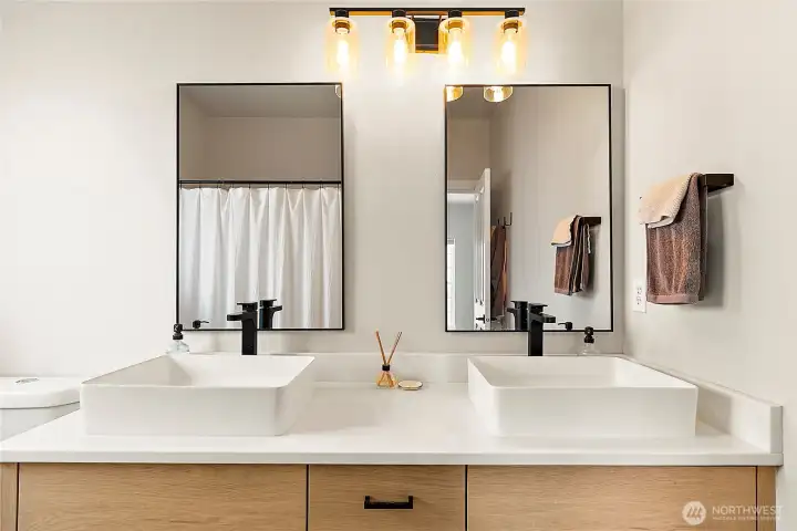 The bathroom features tile floors, new double sinks, modern faucets, new lighting and a fresh quartz counter and cabinets—bringing together beauty and functionality in one luxurious space.