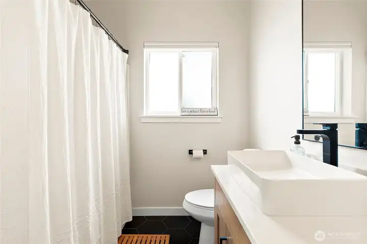 The primary bath feels like a private spa, featuring new tile floors, fresh cabinetry, stylish lighting, and elegant dual sinks.