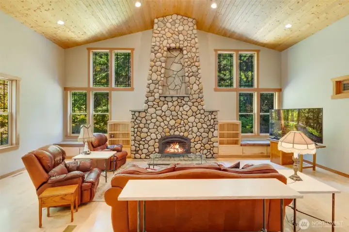 Magnificicant riverock fireplace with soaring wood planked ceilings, tons of windows for natural light and built in storage with window seats!