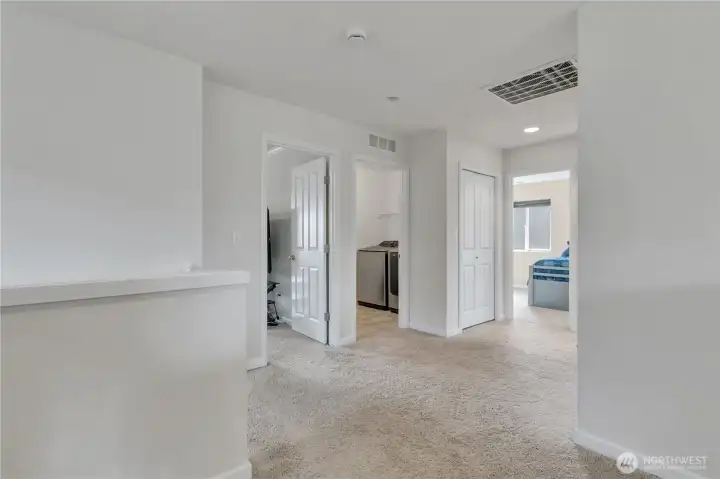 Upstairs hallway looking from 3rd bedroom, towards primary, utility room and 4th bedroom.