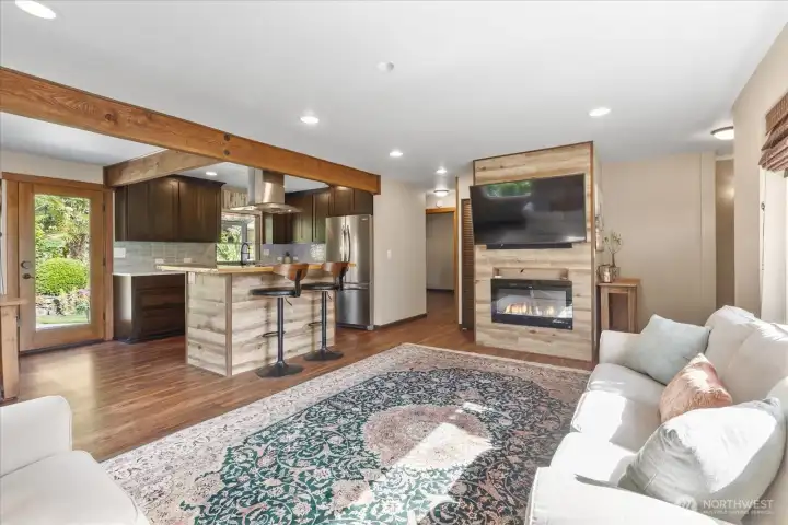 Open concept living area with warm wood accents and a modern electric fireplace. Open concept living area with warm wood accents and a modern electric fireplace.
