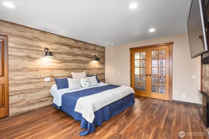 Primary bedroom with beautiful french doors and wall sconce lighting. Primary bedroom with beautiful french doors and wall sconce lighting.