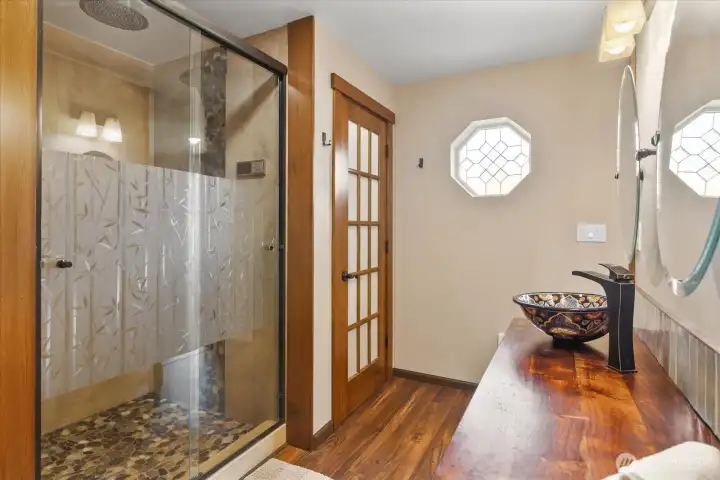 Primary ensuite featuring a tile shower, glass shower doors and private toilet area. Primary ensuite featuring a tile shower, glass shower doors and private toilet area.