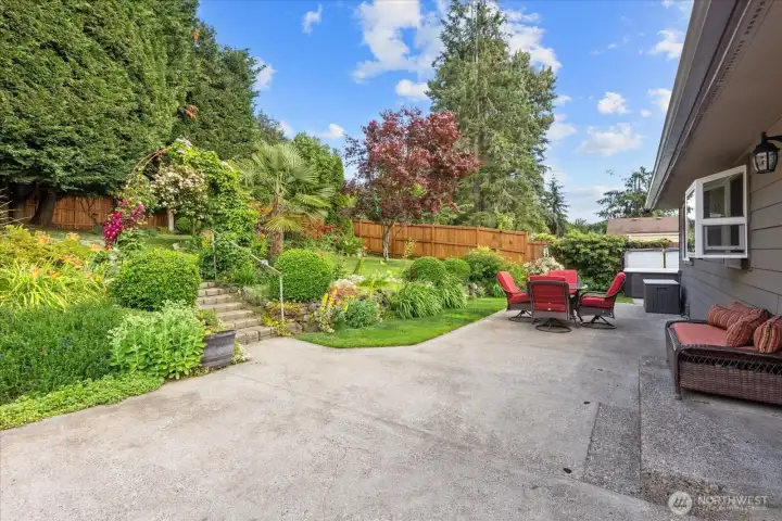 Spacious backyard patio featuring mature landscaping and a beautifully stained privacy fence. Spacious backyard patio featuring mature landscaping and a beautifully stained privacy fence.