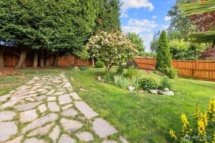 Backyard featuring lawn, a beautiful flagstone pathway, and mature landscaping. Backyard featuring lawn, a beautiful flagstone pathway, and mature landscaping.