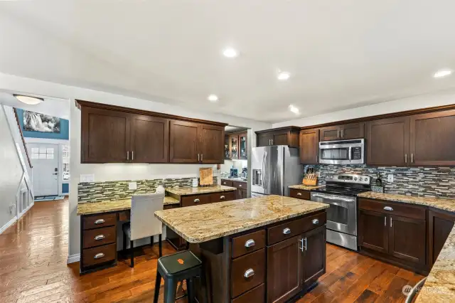 Spacious kitchen with warm wood tones, rich slab granite, hickory floors and cherry cabinets.
