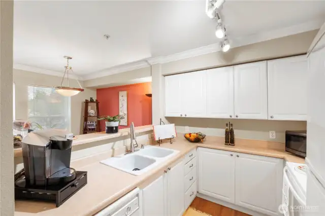Enjoy the ease of a double-basin sink paired with a high-arc faucet—perfect for multitasking in the kitchen. The raised breakfast bar opens to the living and dining areas, allowing you to stay connected with guests or keep an eye on the conversation while preparing meals. Warm-toned counters, updated lighting, and durable flooring tie the space together for both style and function.