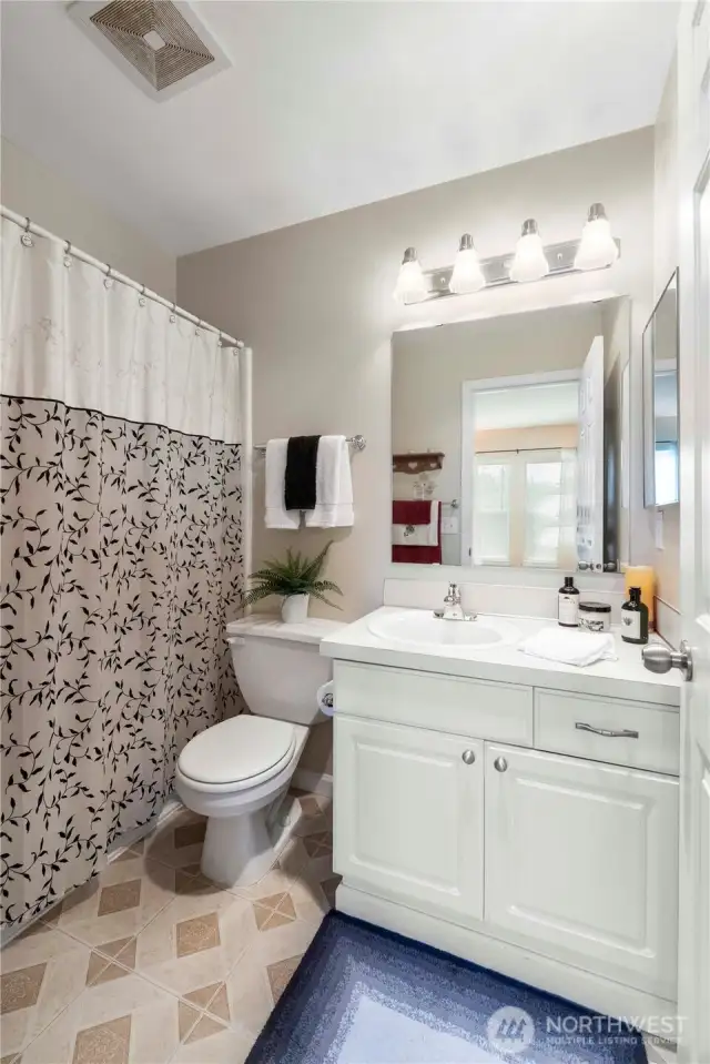 This private en-suite bath offers a clean and functional design with a full tub/shower combo, spacious vanity, and updated lighting. Neutral finishes make it easy to personalize, while the crisp tile flooring adds a touch of durability and style. Perfect for daily routines or unwinding with a relaxing soak.