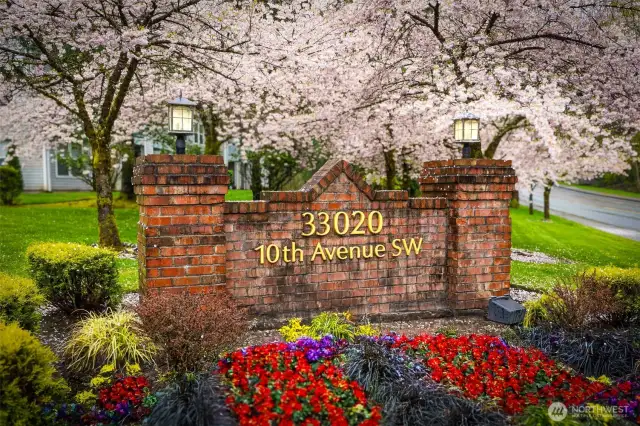 Welcome to 33020 10th Avenue SW—a beautifully maintained community highlighted by this charming brick entry sign, vibrant seasonal landscaping, and a canopy of cherry blossoms in spring. This standout entrance sets the tone for a neighborhood that’s peaceful, well-kept, and full of pride of ownership.