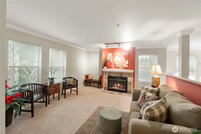 The heart of the living space is anchored by a cozy gas fireplace framed with elegant tilework and a pop of color, perfect for relaxing evenings at home. Enjoy peaceful, tree-lined views from multiple large windows—bringing the outside in while maintaining a sense of calm and privacy.