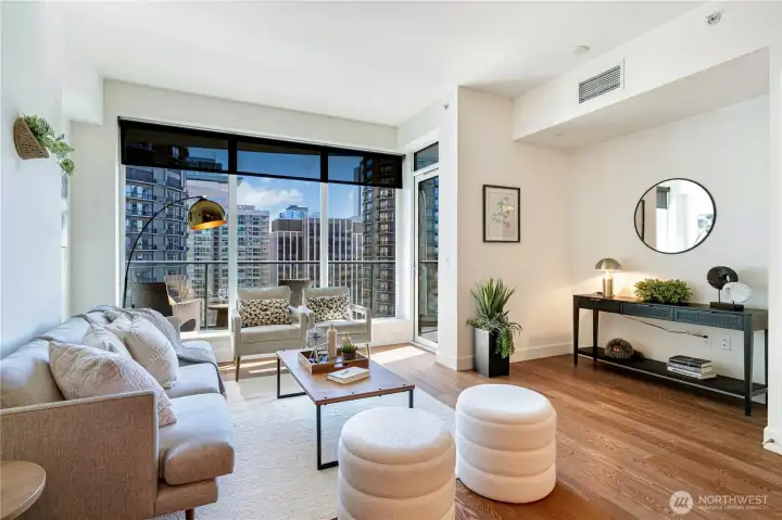 Spacious open-concept living area with floor-to-ceiling windows and sweeping views of Seattle’s vibrant cityscape