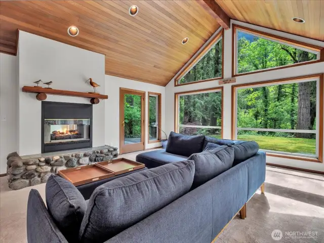 Enjoy the views from the living room with a cozy river rock fireplace.