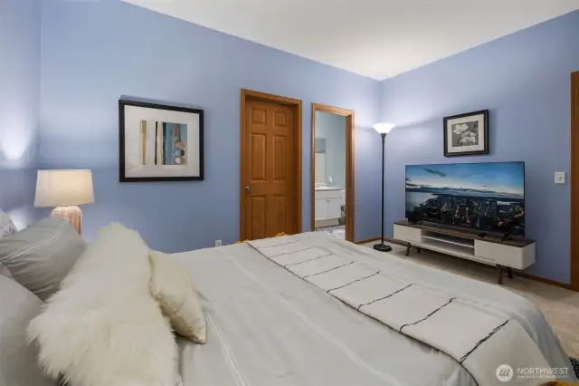 Spacious primary bedroom featuring ample room for a home office and cozy lounge seating. Enjoy the comfort of a generous walk-in closet and an en-suite full bathroom—your perfect retreat for rest, work, and relaxation.