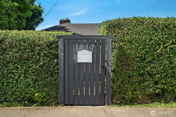 Front gate and landscaped hedge providing privacy from the street.