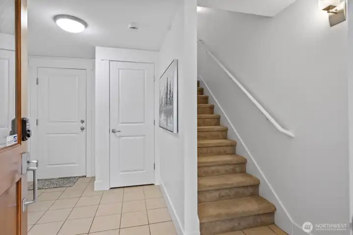 Bright tiled entryway with coat closet and convenient access to the two-car garage. Freshly painted interior with neutral tones and carpeted stairs leading to the main level.