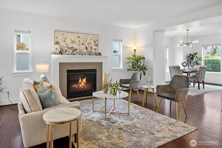 Spacious main-level living area featuring gas fireplace, large windows, and open flow to dining and kitchen.