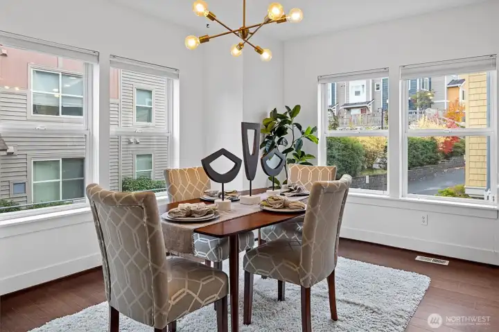 Light-filled dining area surrounded by windows overlooking tree-lined streets.