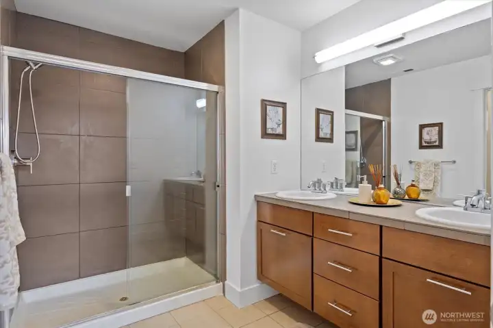 Primary bath features dual sinks, large mirror, and walk-in shower with tile surround.