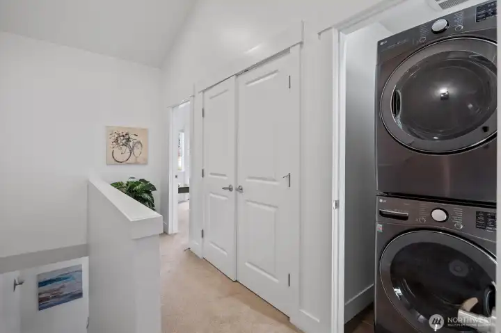 Upper-level hallway with vaulted ceiling and convenient laundry area with full-size washer and dryer.