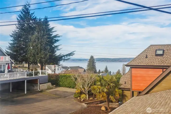 From the north bedroom, look out over the neighborhood rooftops to Puget Sound and the distant shore.